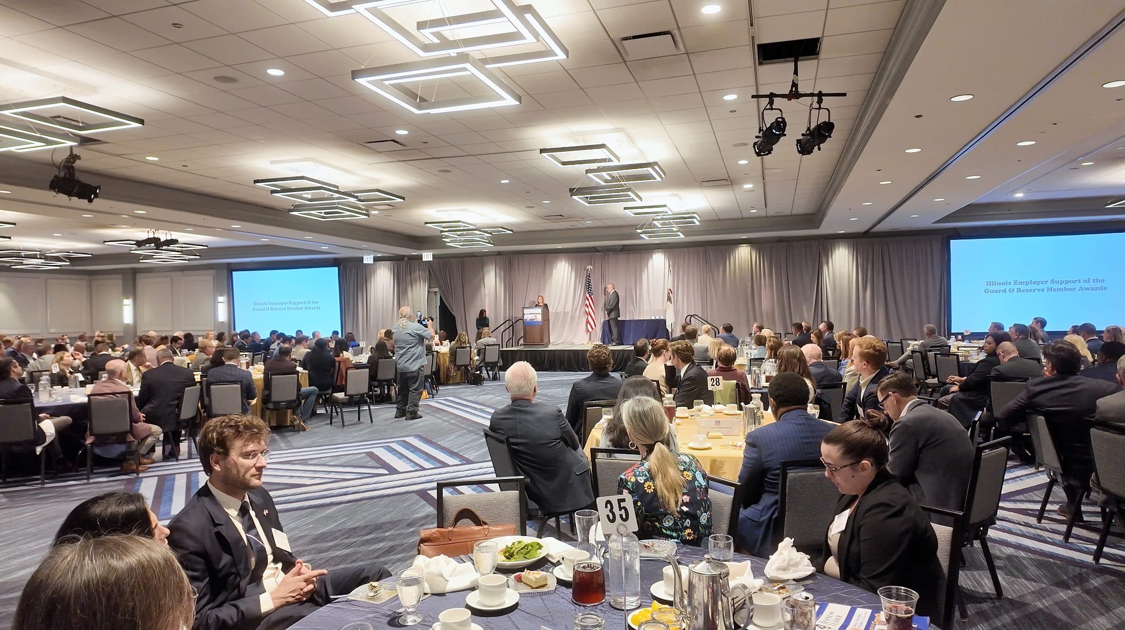Wide view of the Hilton Chicago ballroom during the luncheon, with guests at round tables facing the stage.