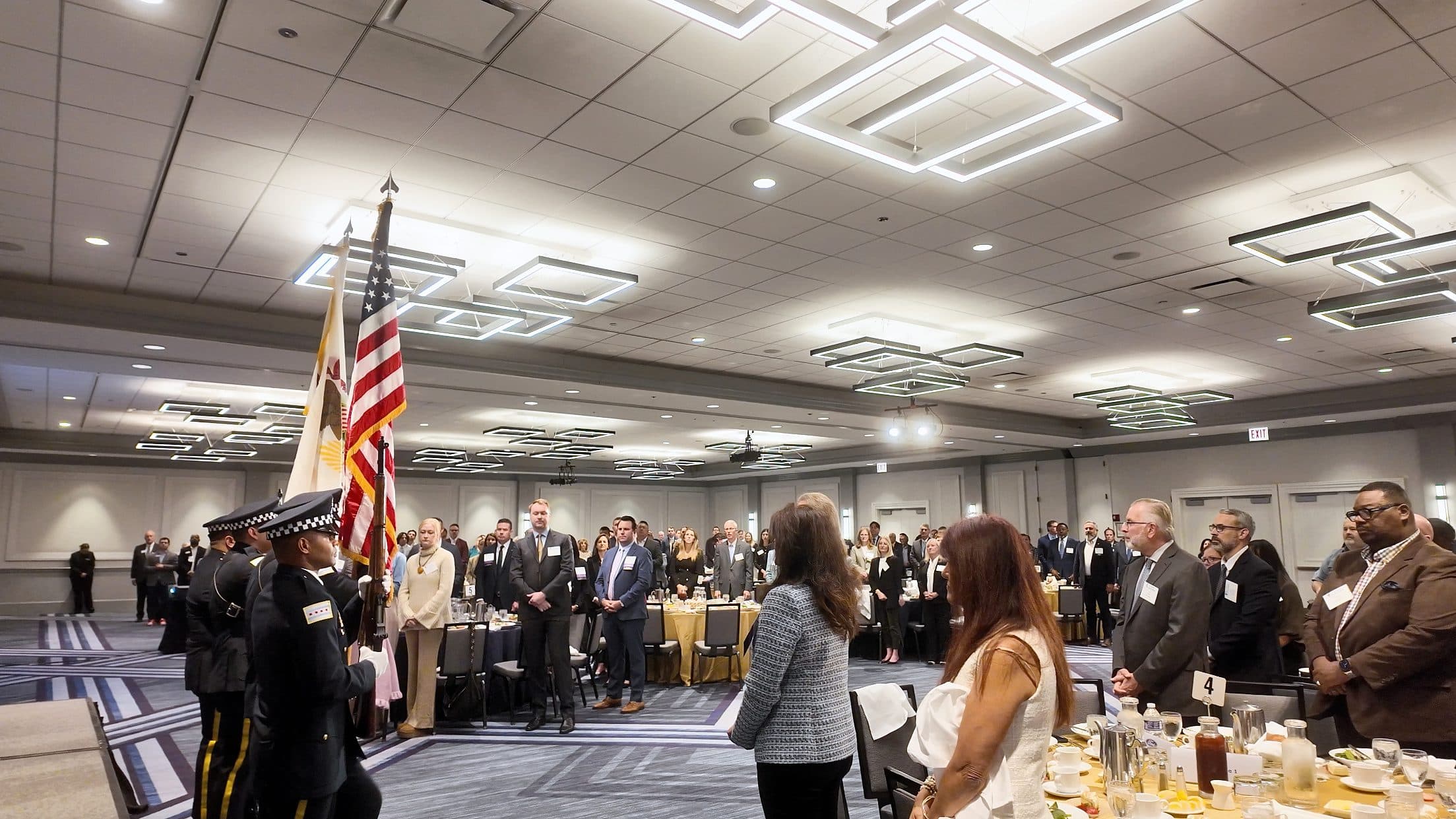 An honor guard presents the colors as attendees stand in the ballroom.