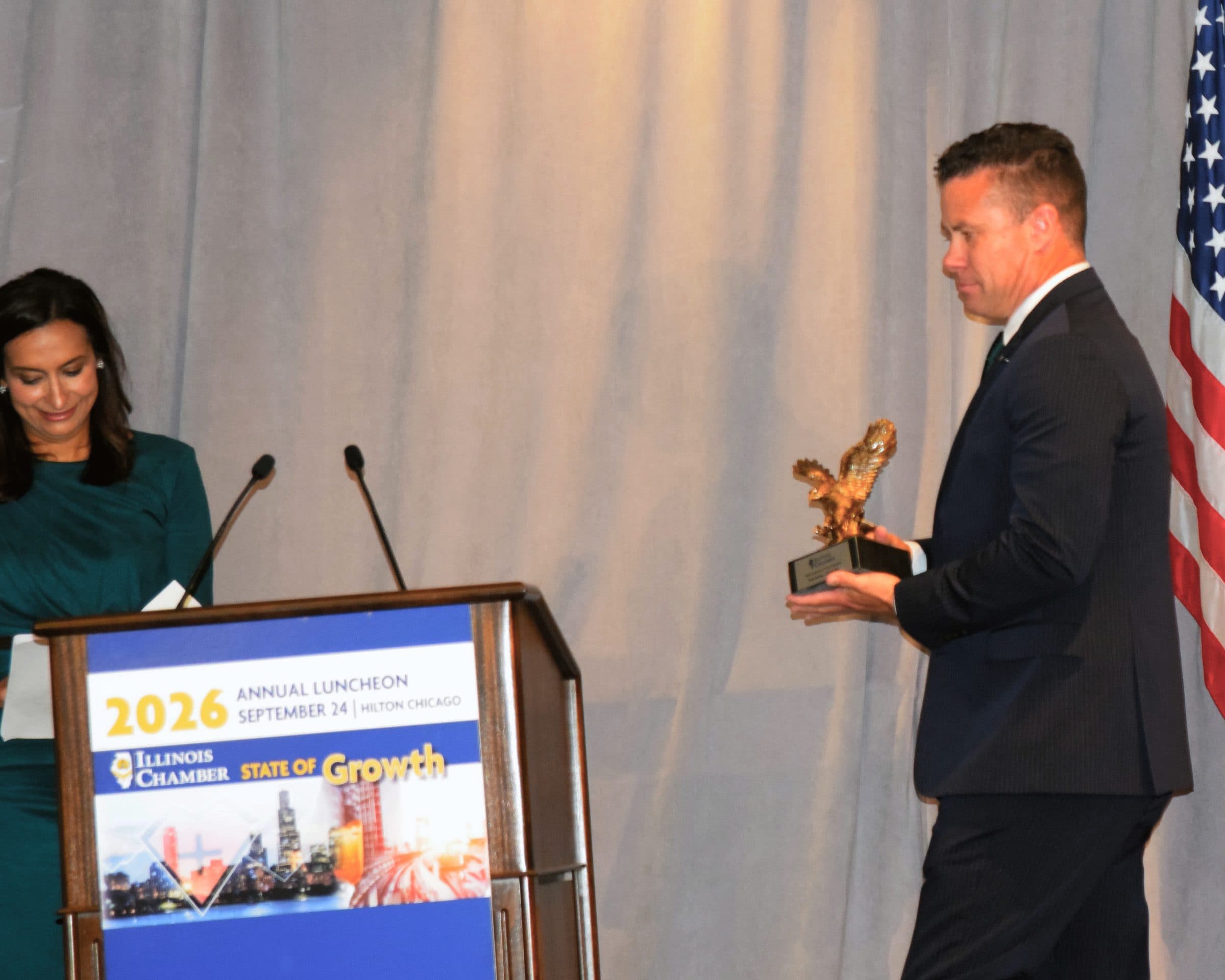 An honoree carries an eagle statuette across the stage.