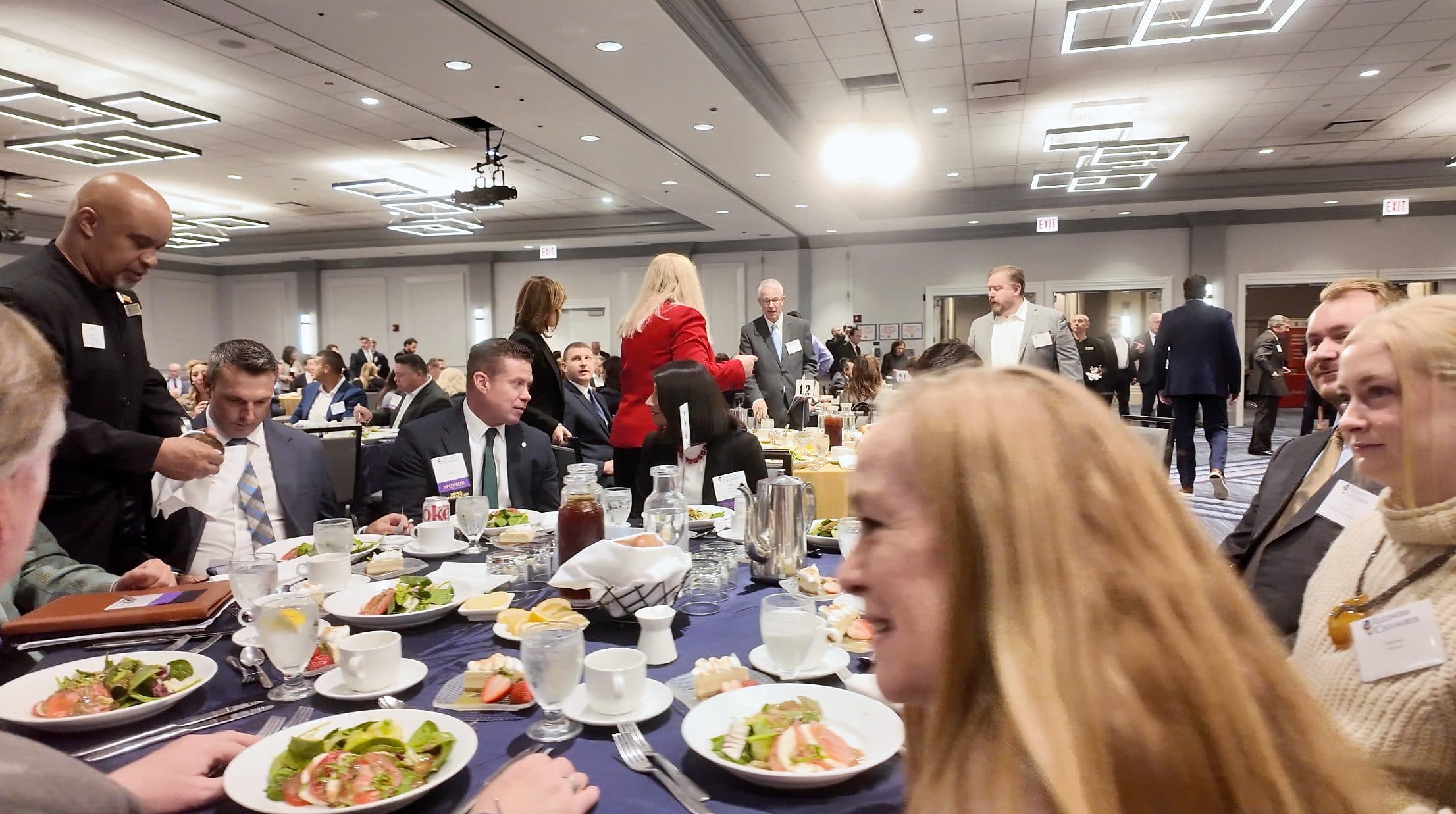 Guests seated for lunch near the front of the ballroom.