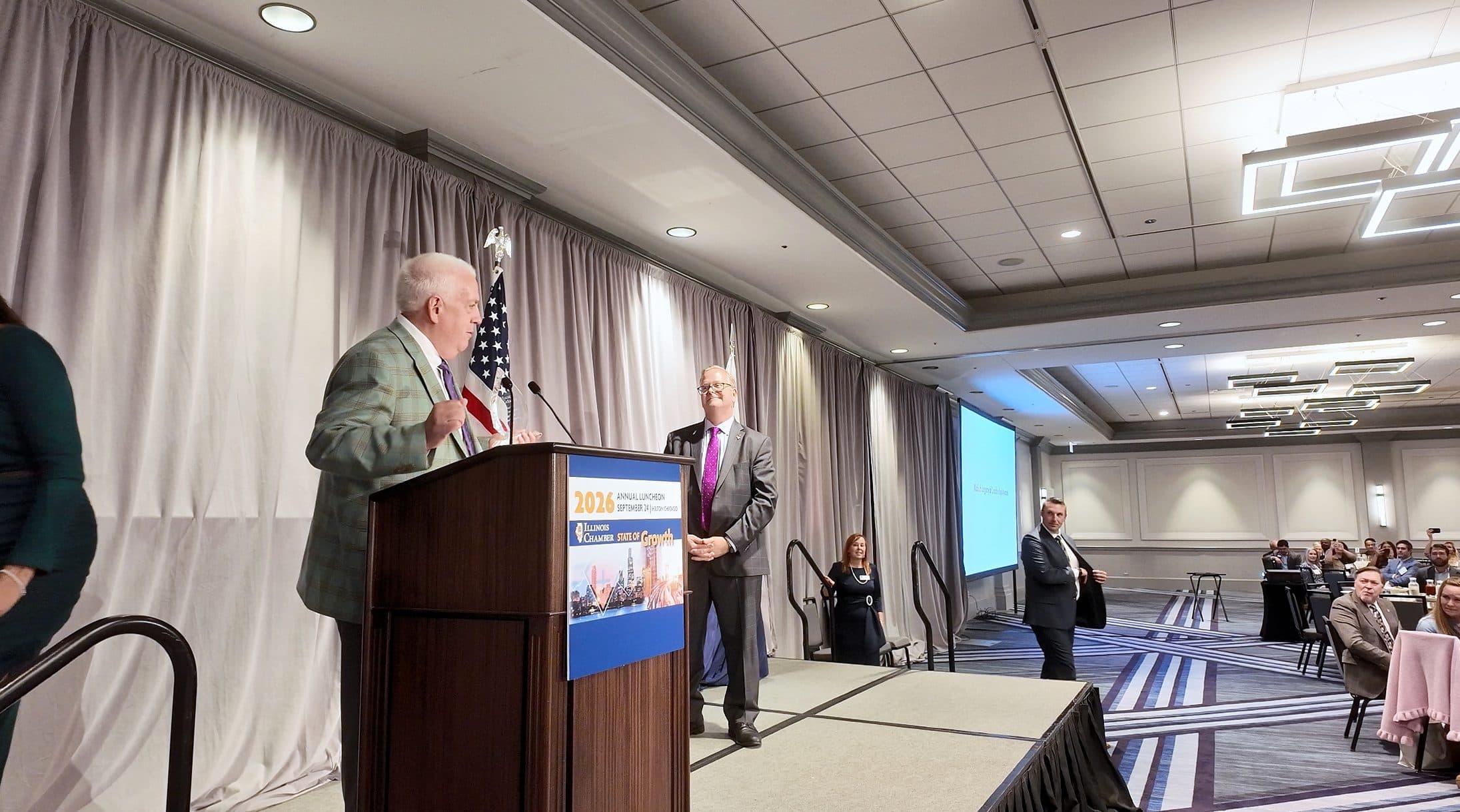 Two speakers share the stage at the podium.
