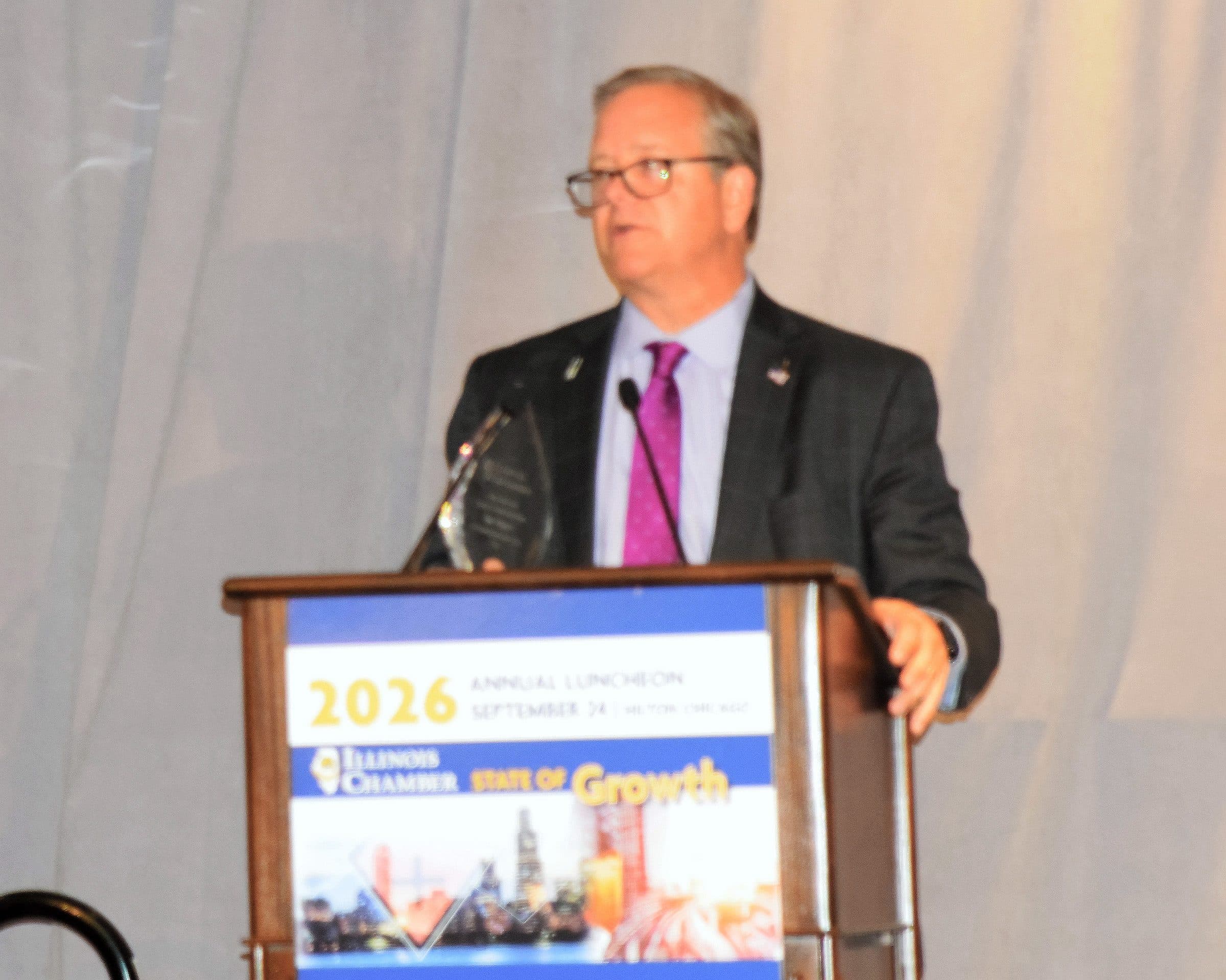 A speaker at the podium beside a crystal award.