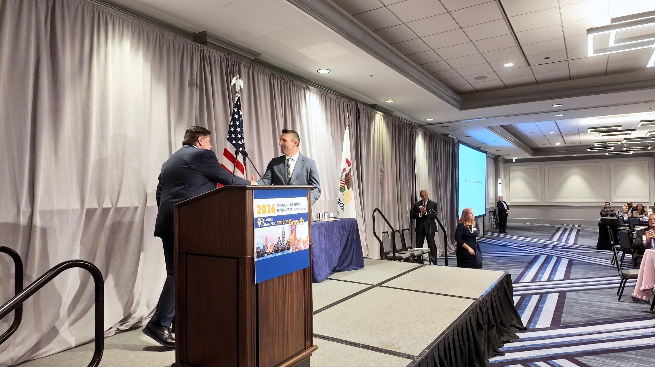 Two men shake hands at the podium.