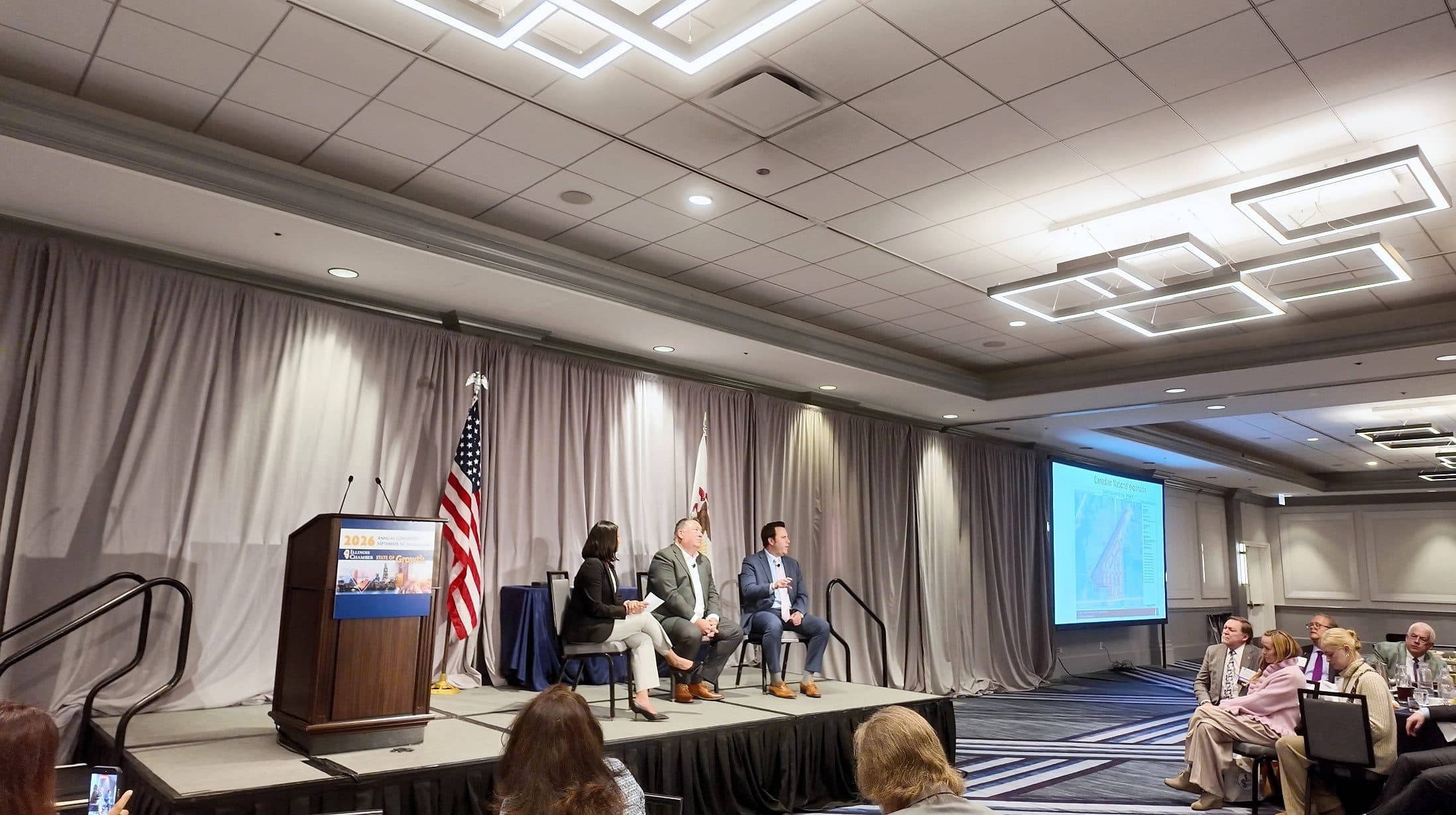 The panel discussion on stage, seen from the side of the ballroom.