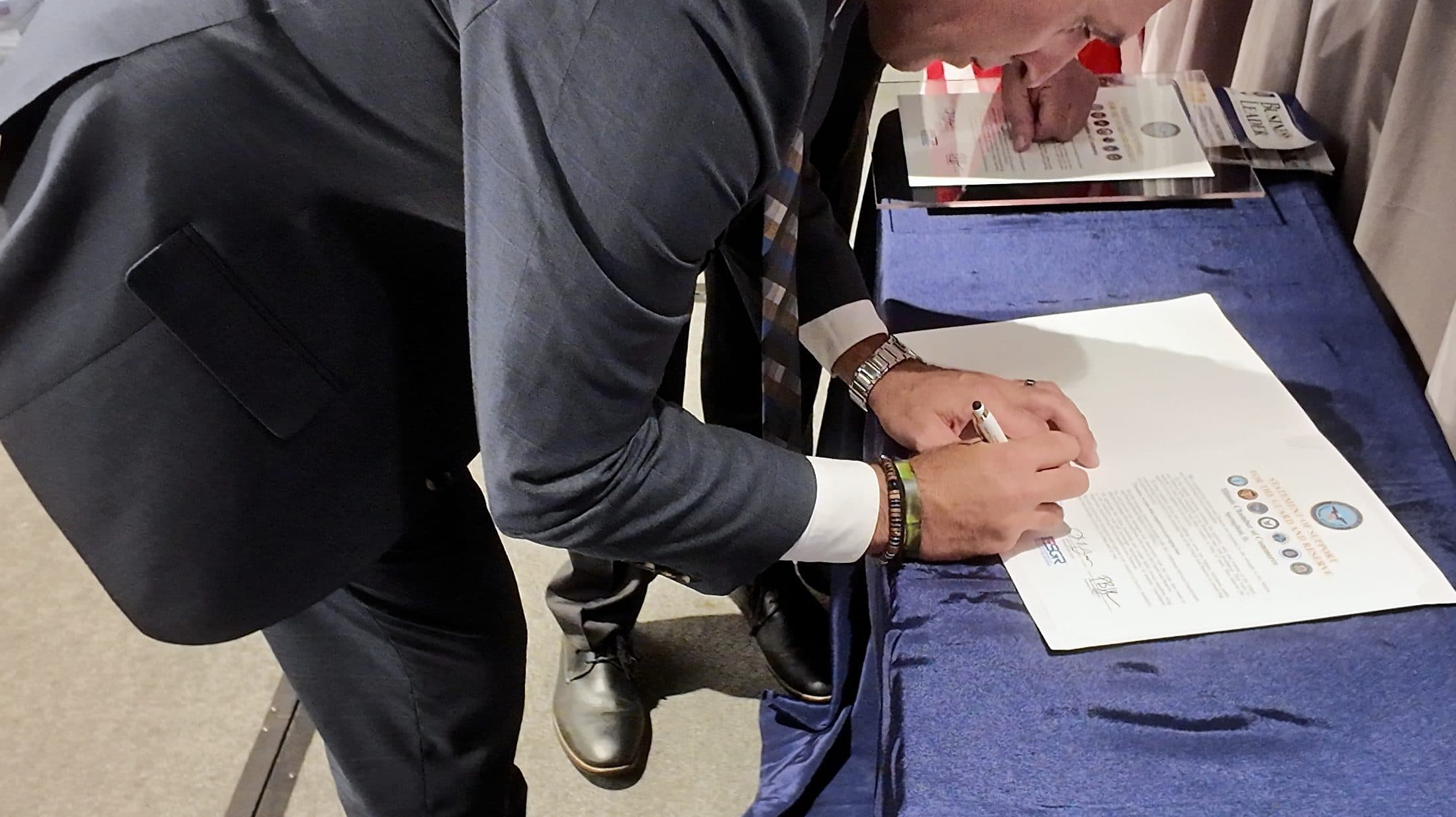 Close-up of a man signing a certificate.